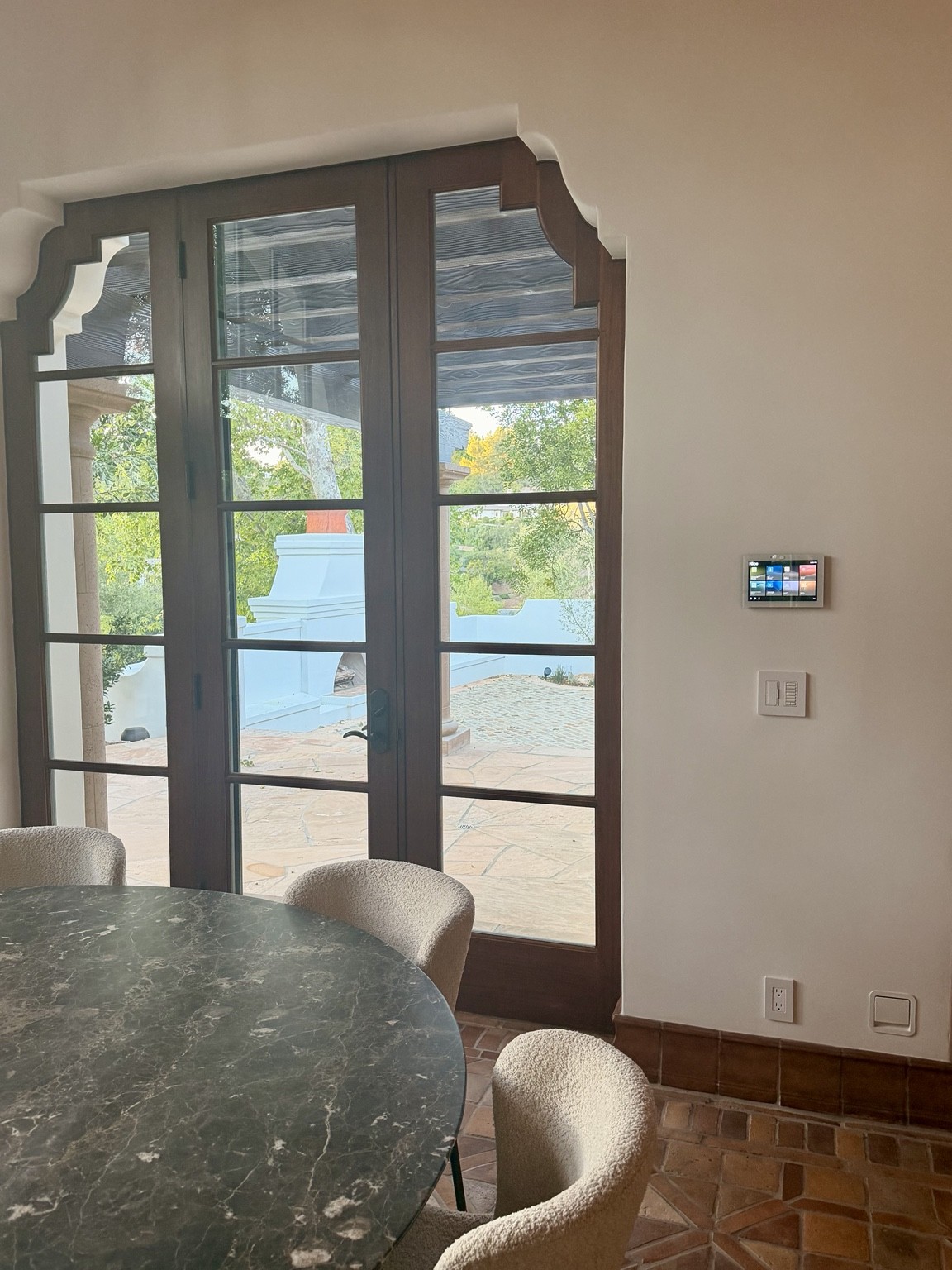 Wall-mounted touchscreen in the dining area beside glazed patio doors