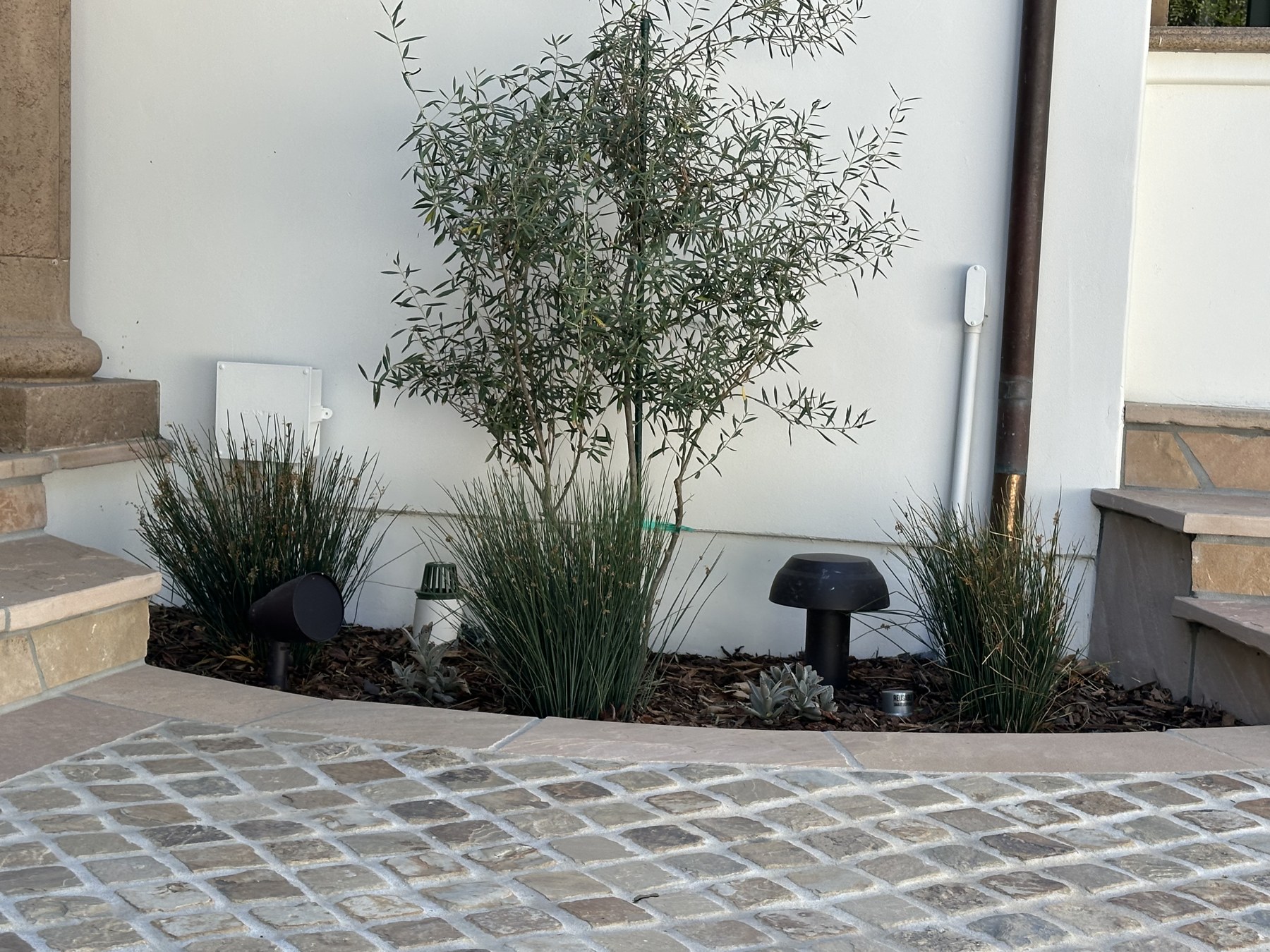 Outdoor speakers placed within landscaping beside the home